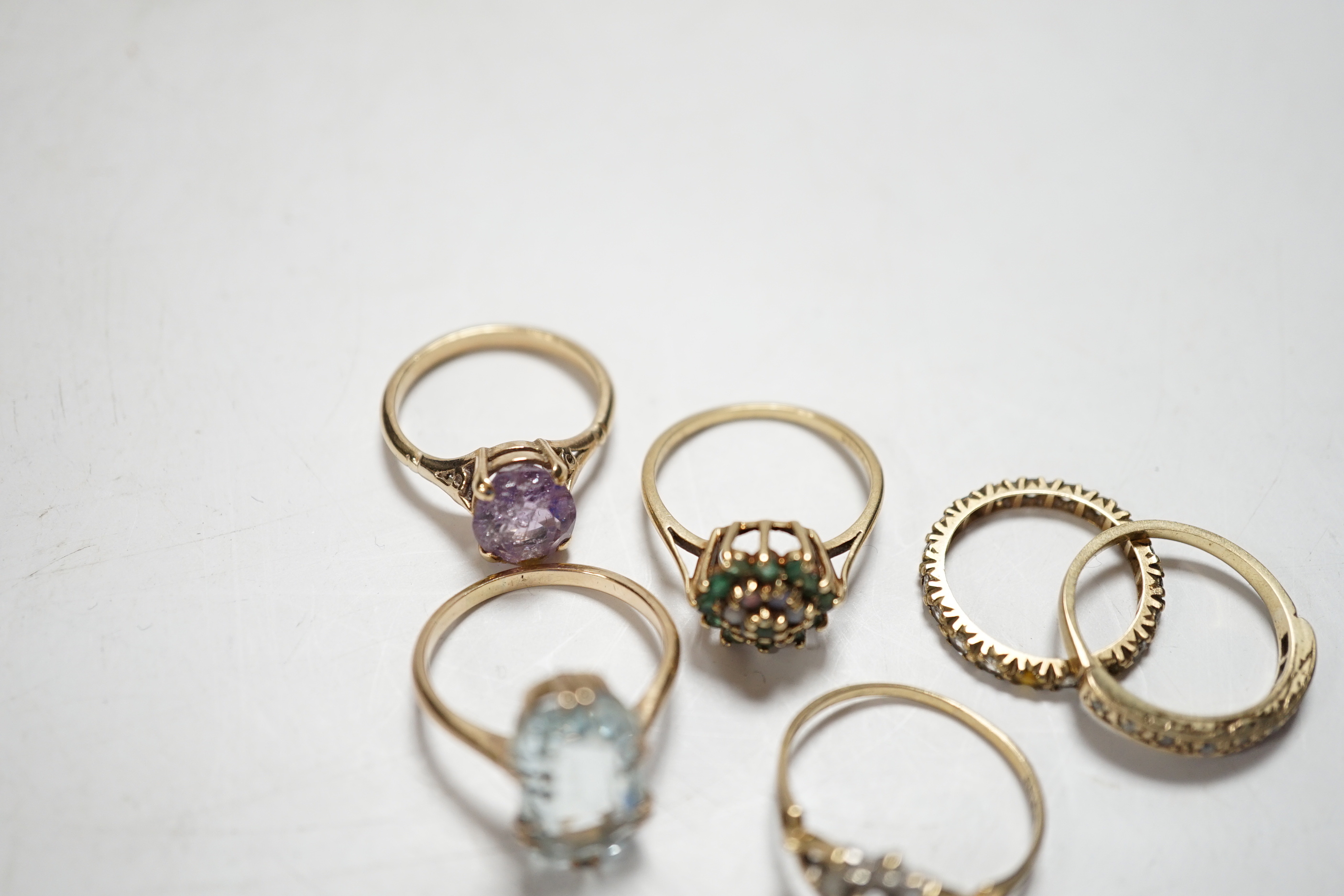 Four assorted modern 9ct and gem set rings including cubic zirconia, two other yellow metal and gem set rings including aquamarine and a yellow metal and multi gem set stick pin, gross weight 15.8 grams.